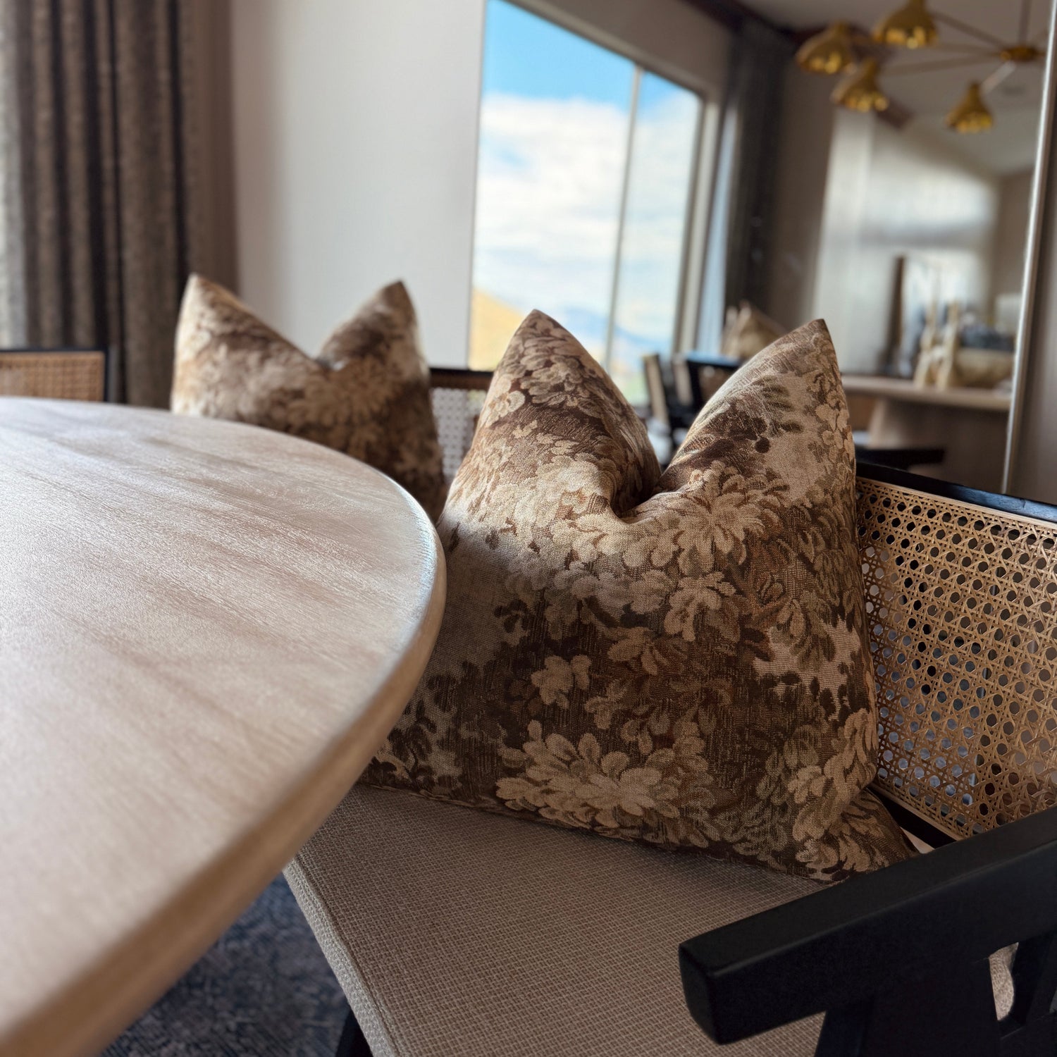 Dining room with floral-patterned cushions on a chair, round table, and large mirror.
